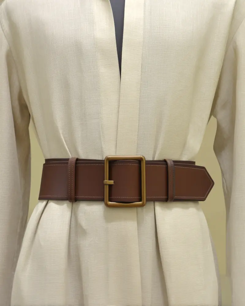 A cream garment with a brown leather belt on a dress form